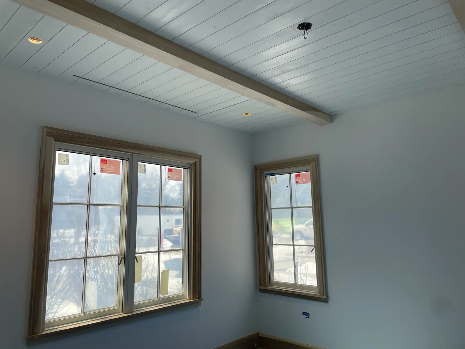 Shiplap ceiling with exposed beam and wood-trimmed windows installed by Gerhard and Sons